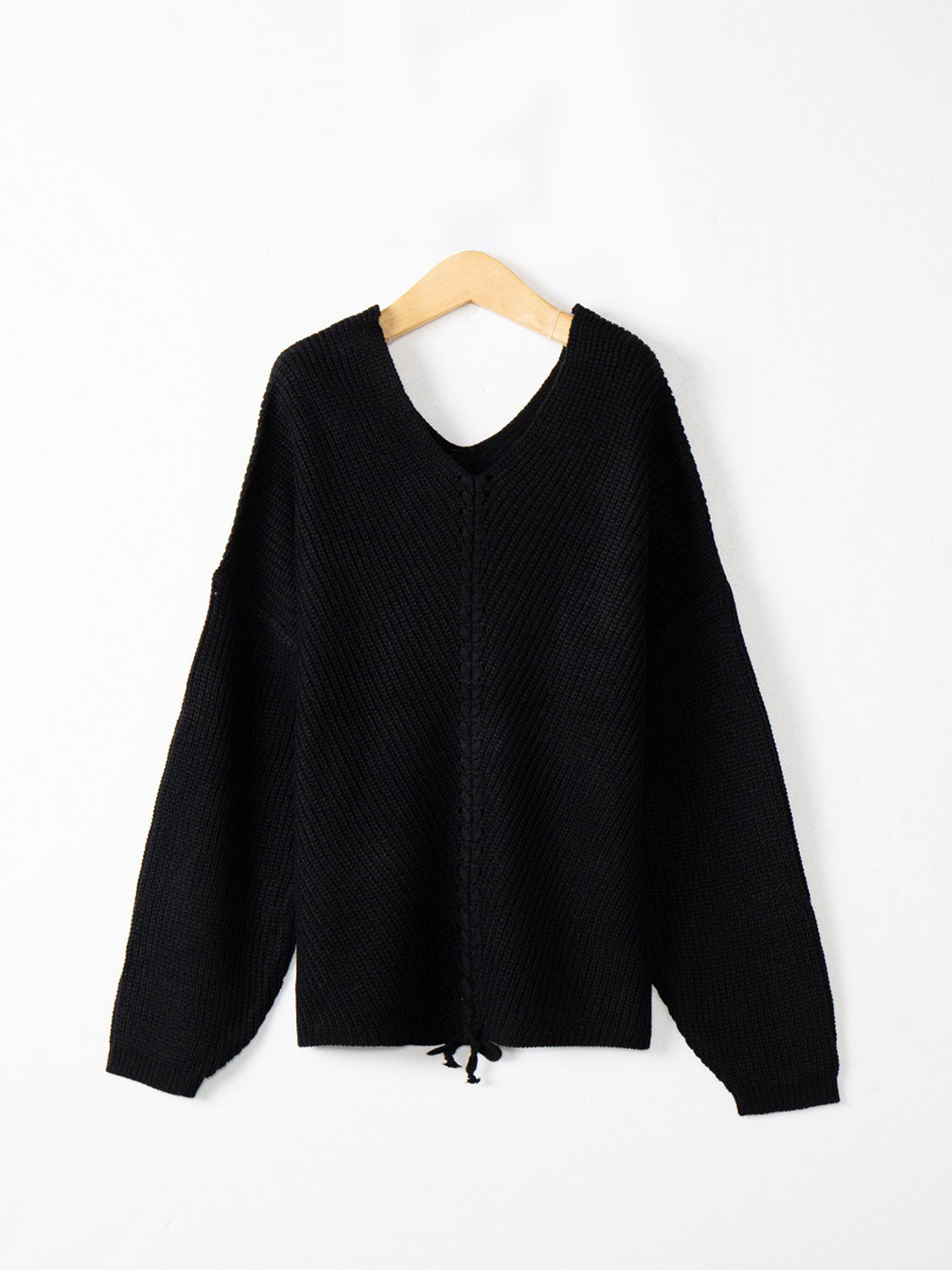 Black knit sweater with V-neck and lace-up detail at hem