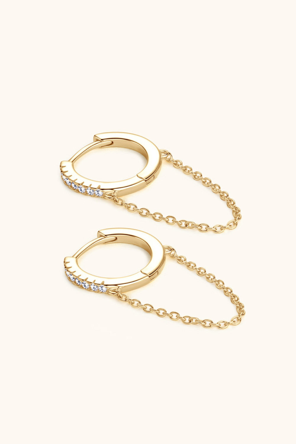 Gold dangling chain pavé huggie earrings with delicate cubic zirconia stones.