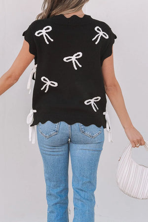 Black knit vest with white bow print, scalloped hem, and side ties.