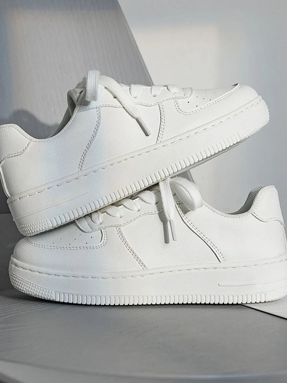 White minimalist platform sneakers with lace-up closure and textured sole.