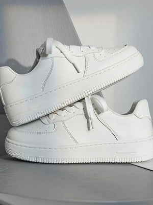 White minimalist platform sneakers with lace-up closure and textured sole.