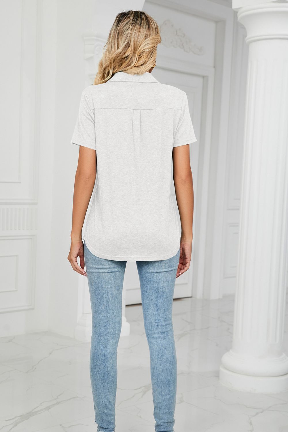Light gray short sleeve V-neck polo with pocket detail and a curved hem.