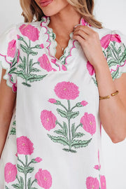 White cotton blouse with vibrant pink floral print, scalloped neckline and short sleeves.