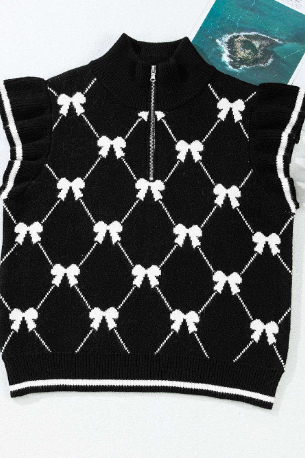 Black knit zip vest with white diamond bow pattern and ruffled sleeves.