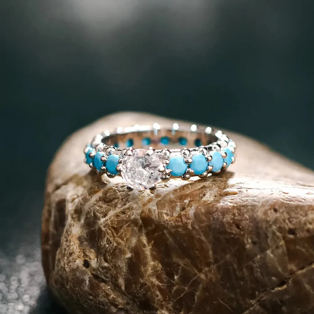 Turquoise bezel & solitaire ring in sterling silver with a clear center stone and turquoise accents.