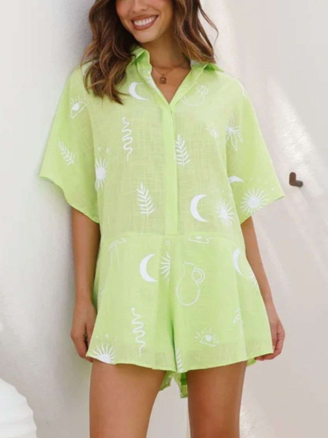 Light green celestial print linen romper with short sleeves and button front.
