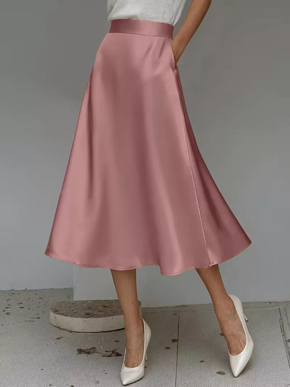 Pink satin A-line skirt with pockets and a midi length.