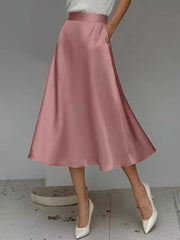 Pink satin A-line skirt with pockets and a midi length.