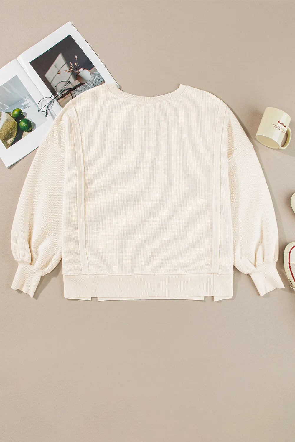 Ivory waffle knit pullover sweater with slit sleeves and a crew neck.