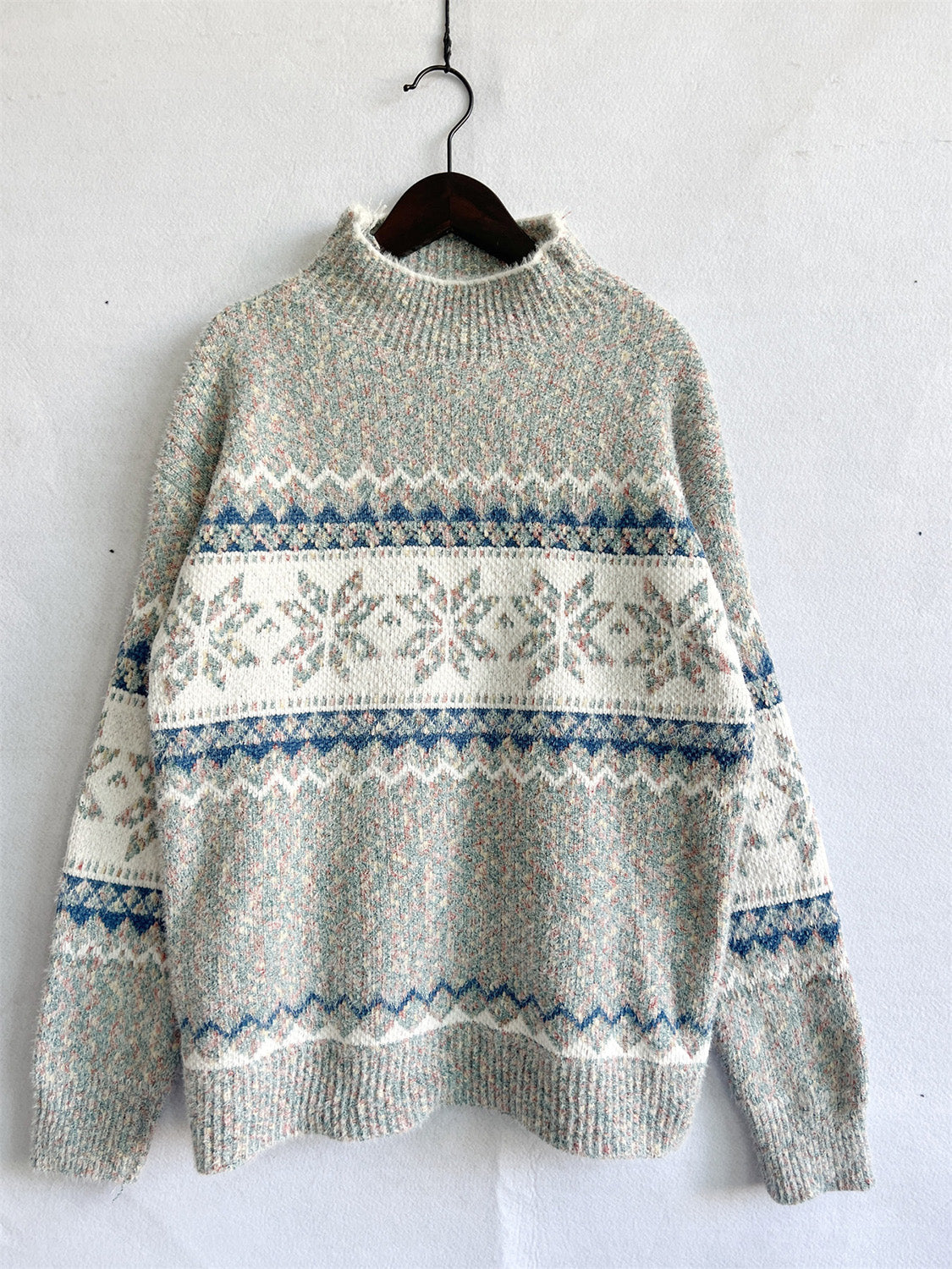 Geometric knit mockneck pullover with snowflake and chevron patterns in pastel colors.