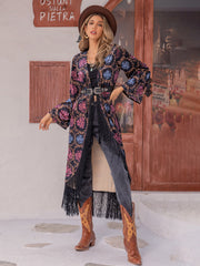 Bohemian duster with multicolor floral print, fringe trim, and bell sleeves.