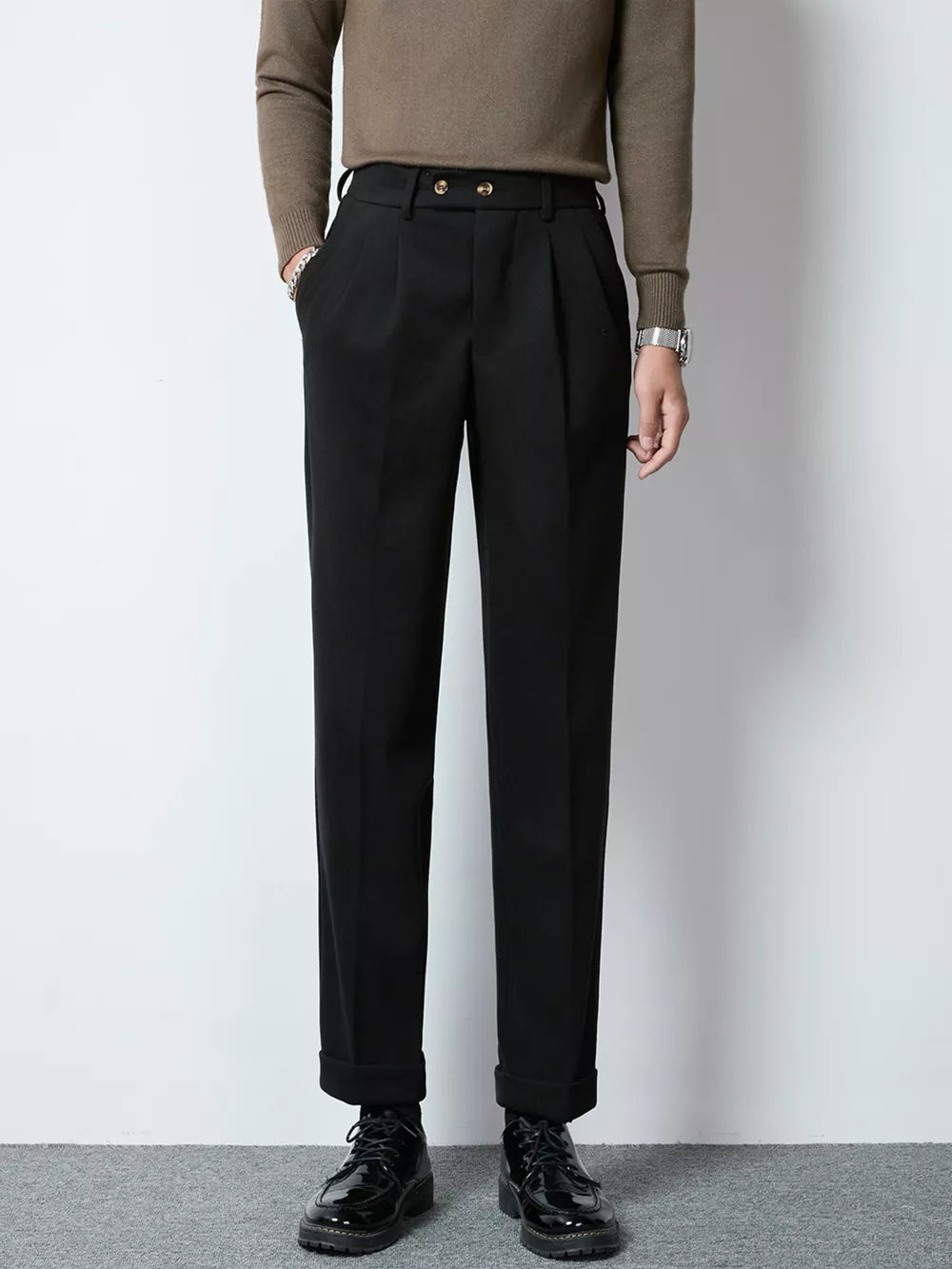 Men's black tailored pleated trousers with cuffed hems and double button closure.