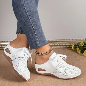 White perforated lace-up mule flats with cut-out sides and white laces.