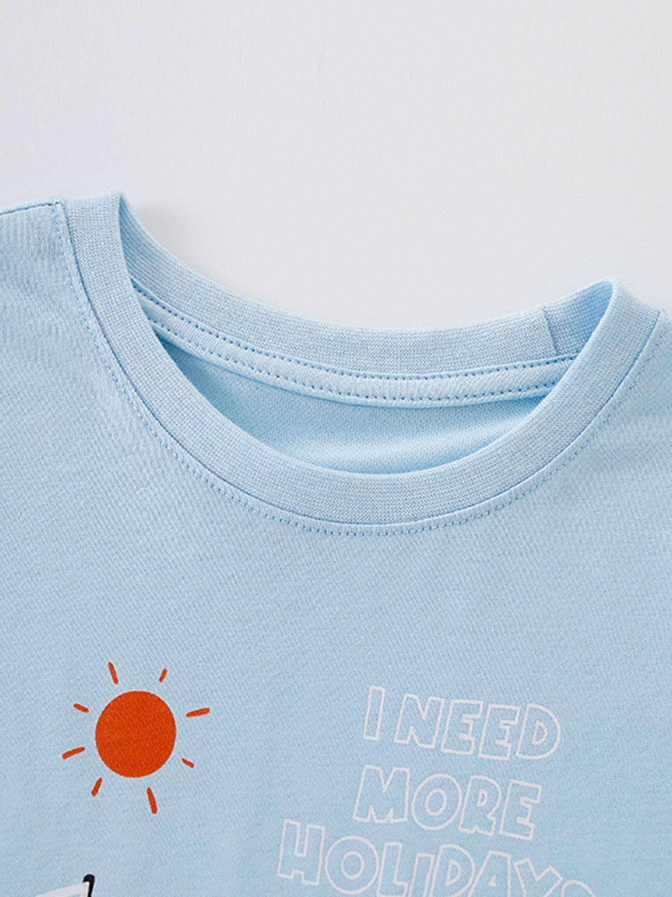 Light blue cotton baby t-shirt with sun graphic and text I NEED MORE HOLIDAYS