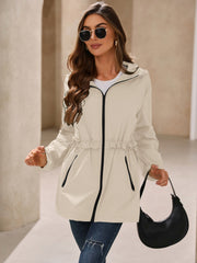 Lightweight hooded jacket in tan with ruffled waistline and black trim.