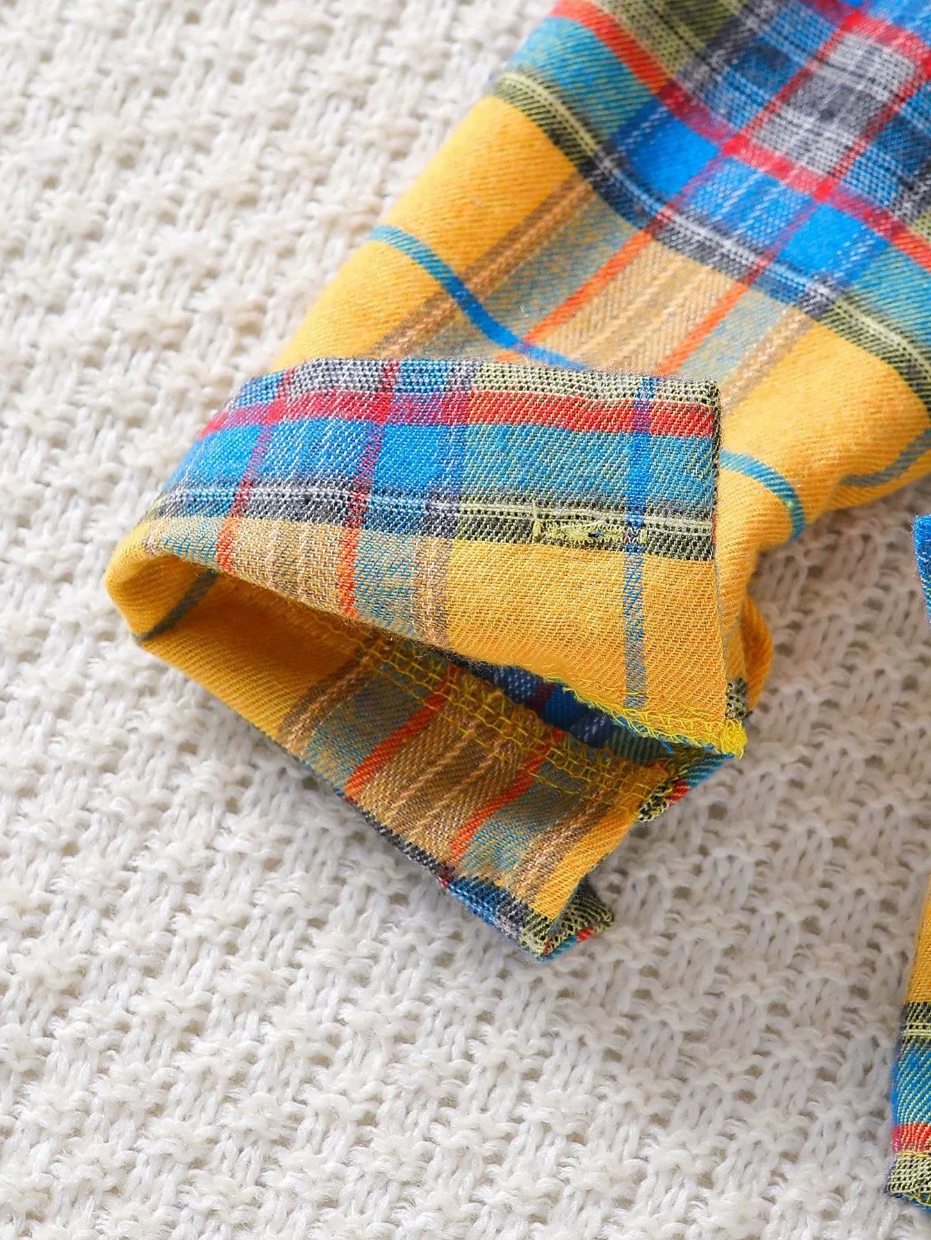 Baby cotton plaid shirt cuff detail in yellow, blue, and red plaid.