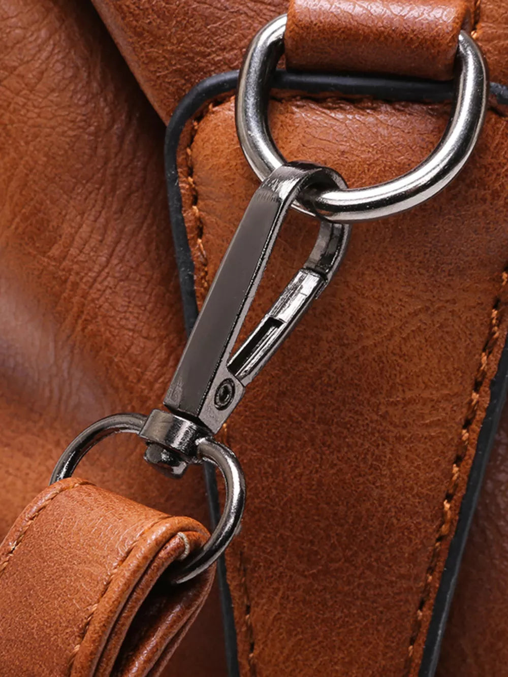 Brown leather half-moon bag detail with silver buckle and strap hardware.