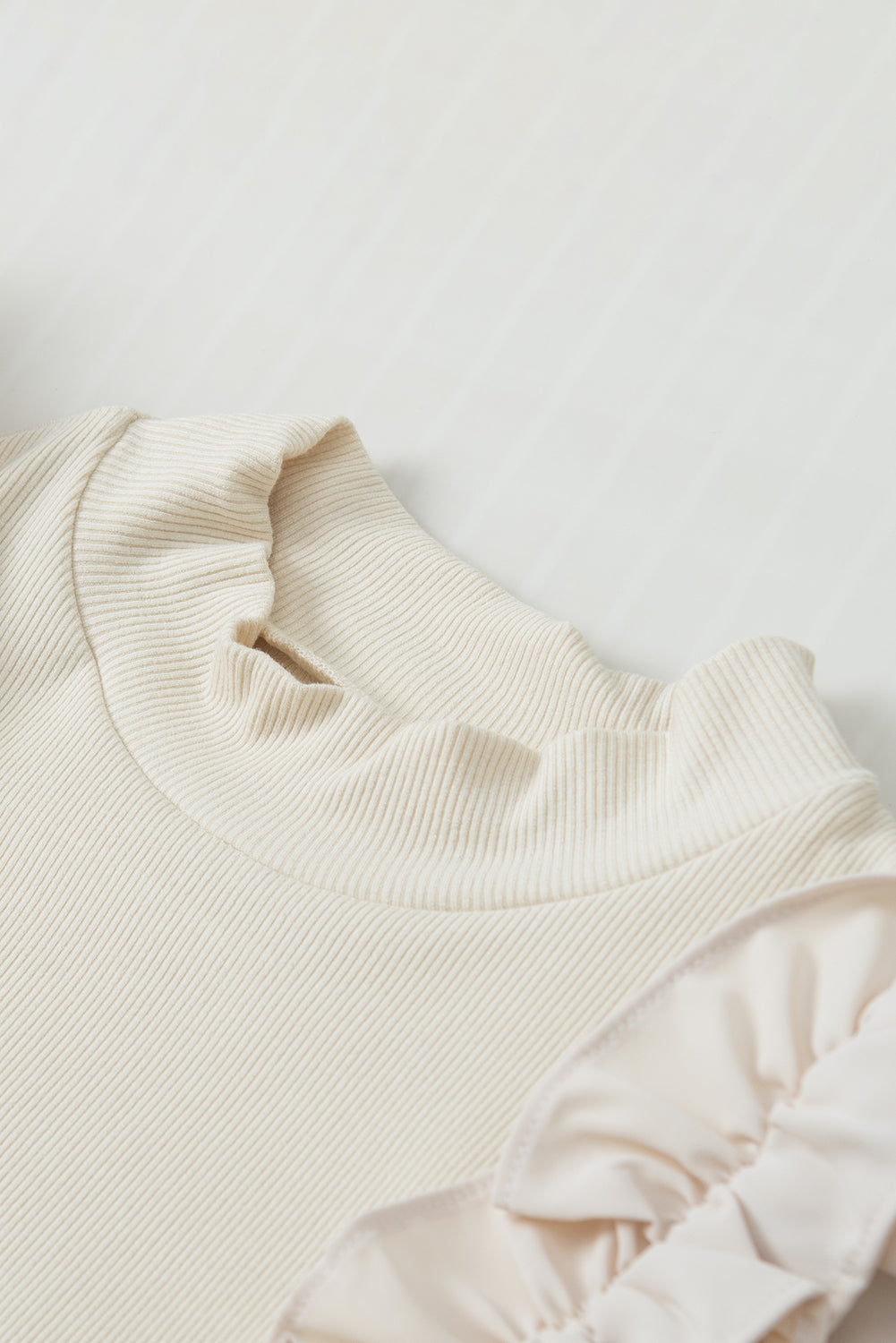 Beige ribbed mock neck top with ruffled sleeves and neckline detail