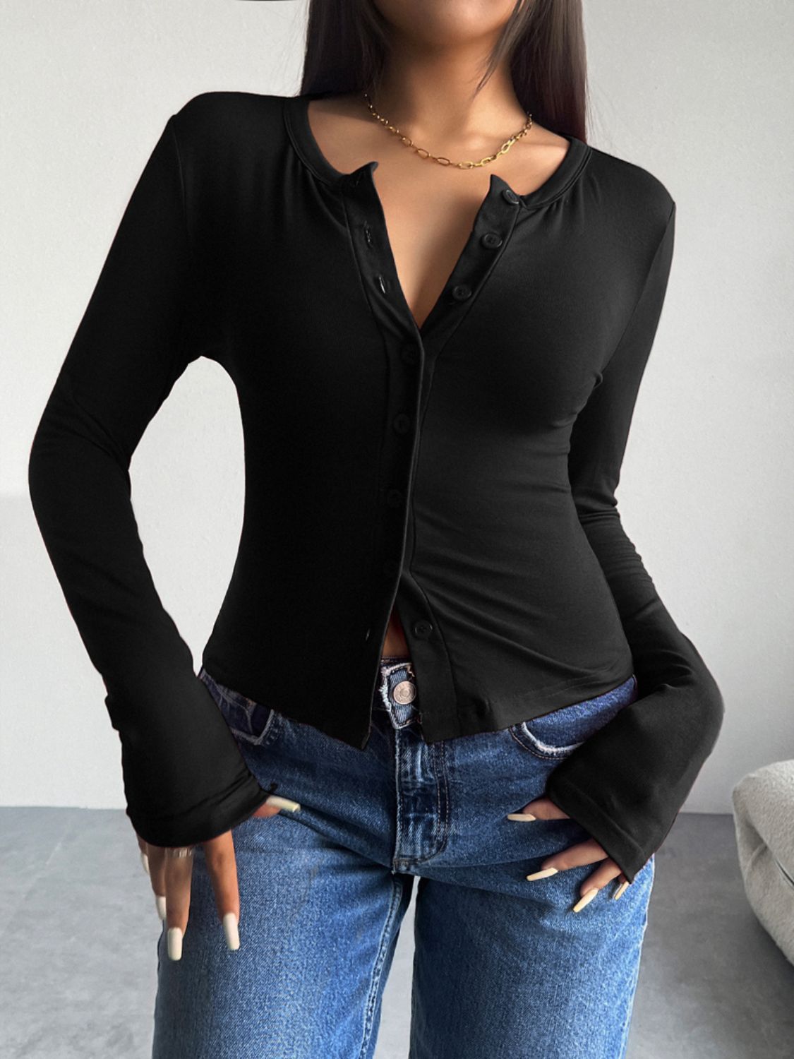 Black button-up cardigan with a round neckline and long sleeves, styled with jeans.