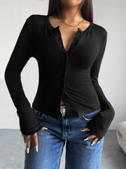 Black button-up cardigan with a round neckline and long sleeves, styled with jeans.