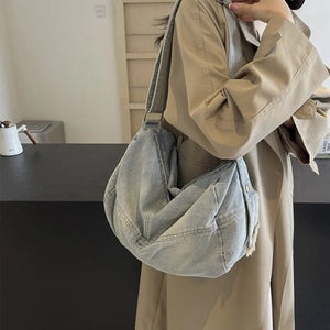 Washed denim hobo bag in light blue with a slouchy silhouette and frayed detail.