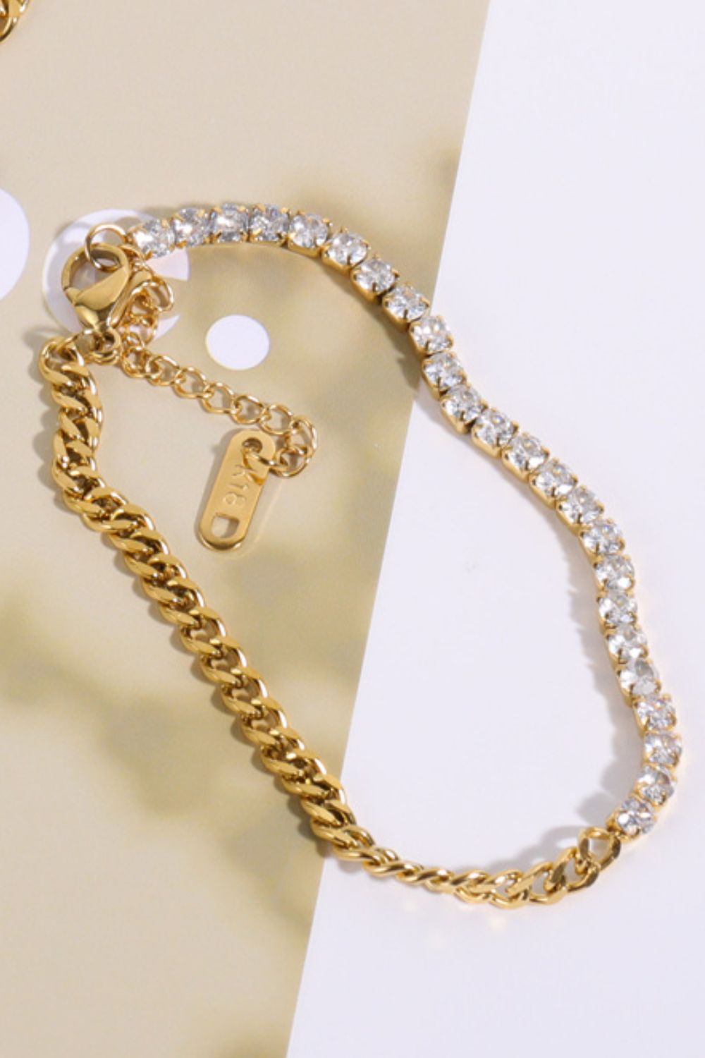 Gold dual-chain bracelet with a line of clear cubic zirconia stones and a cuban link chain.