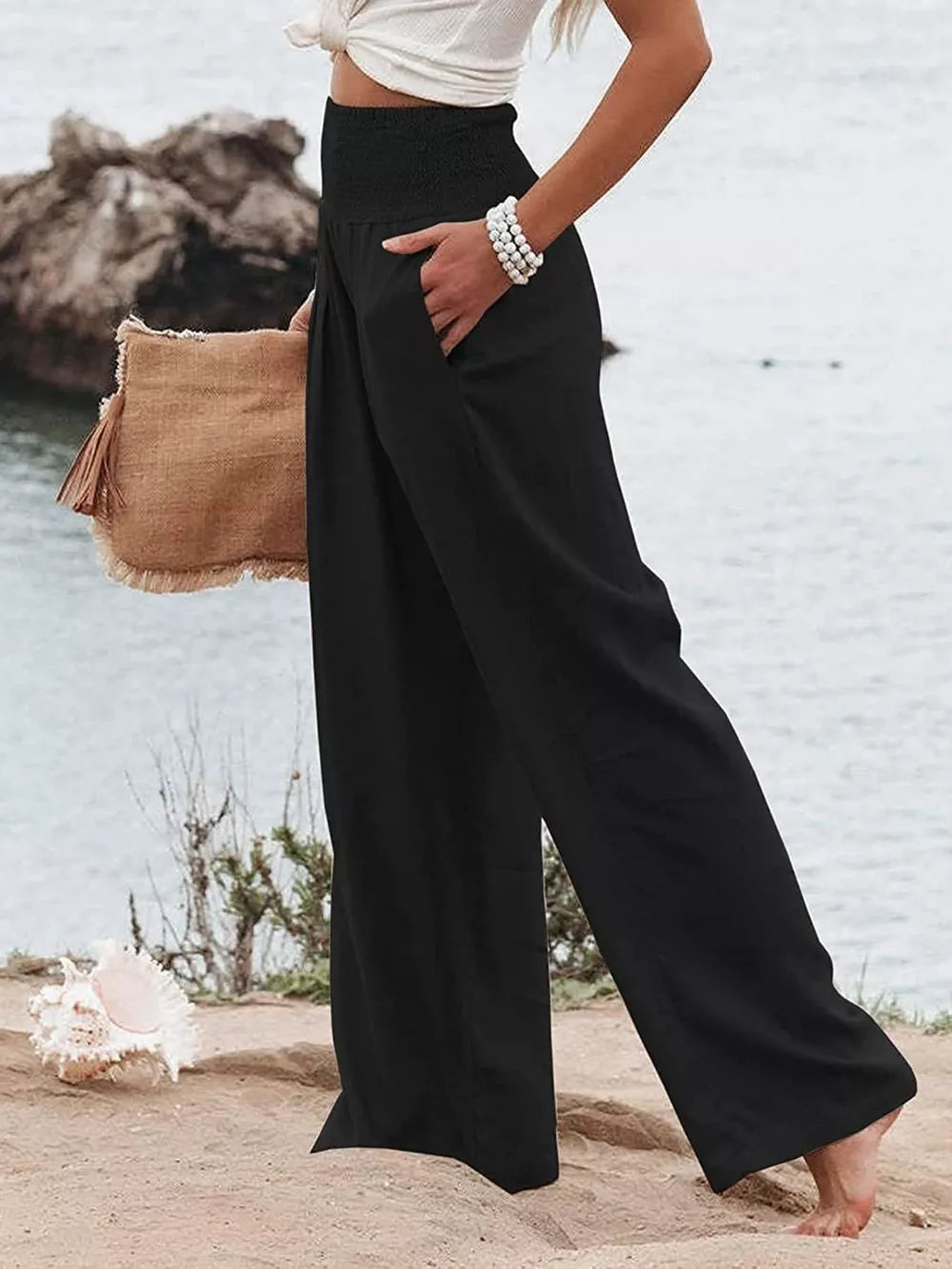 Black smocked maternity pants with wide legs and pockets, styled with a white top.