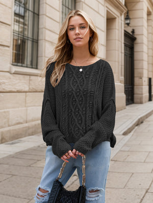Black cable knit cocoon sweater with crew neck and long sleeves.