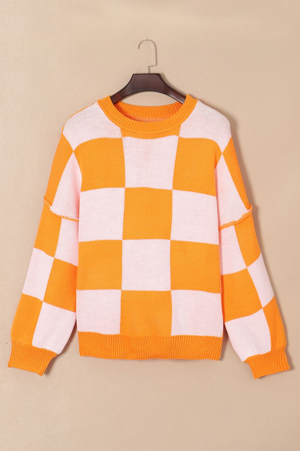Checkerboard knit crewneck sweater in orange and white with balloon sleeves.
