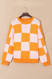 Checkerboard knit crewneck sweater in orange and white with balloon sleeves.