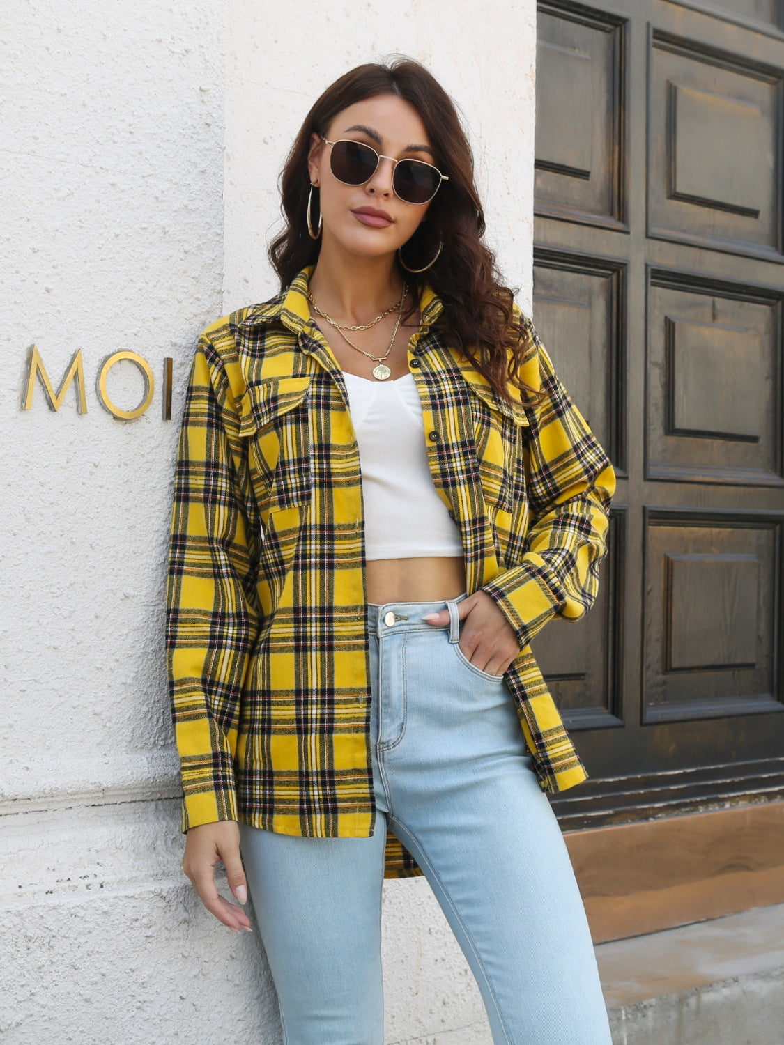 Yellow plaid overshirt with flap pockets worn open over a white crop top and light wash jeans.