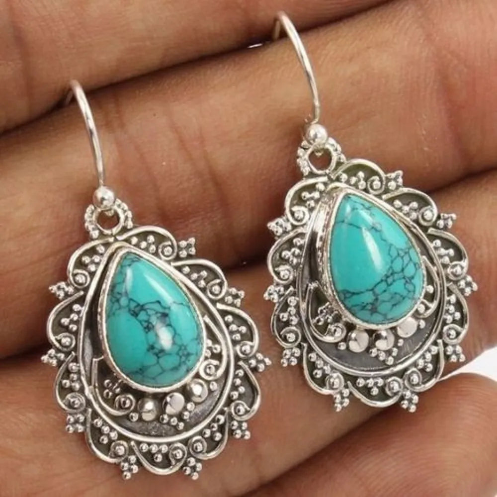 Turquoise teardrop filigree statement earrings with intricate metalwork.
