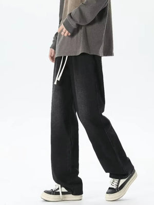 Men's relaxed fit jeans with gradient wash and white drawstring waist.