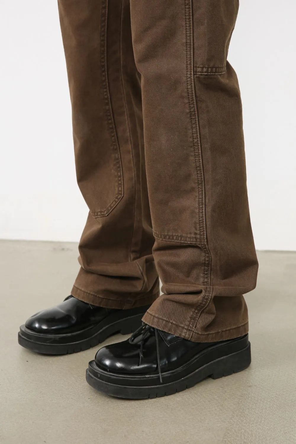 Utility-inspired carpenter trousers in coffee brown with reinforced knees and contrast stitching.