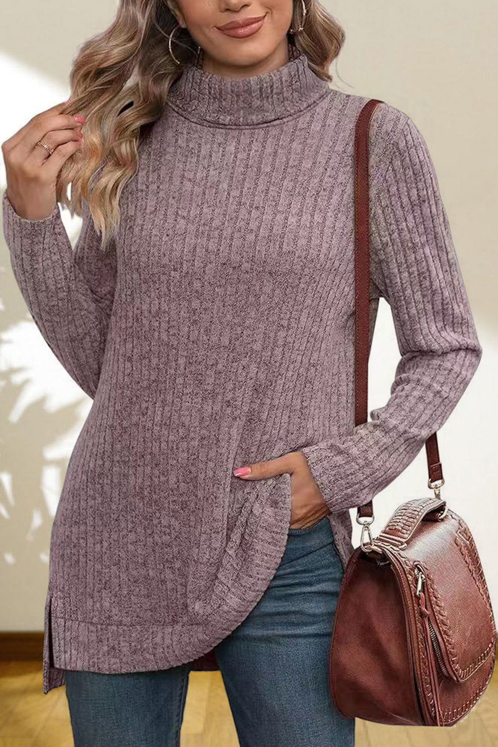 Ribbed knit turtleneck tunic top in lavender with side slits, styled with jeans and a crossbody bag.