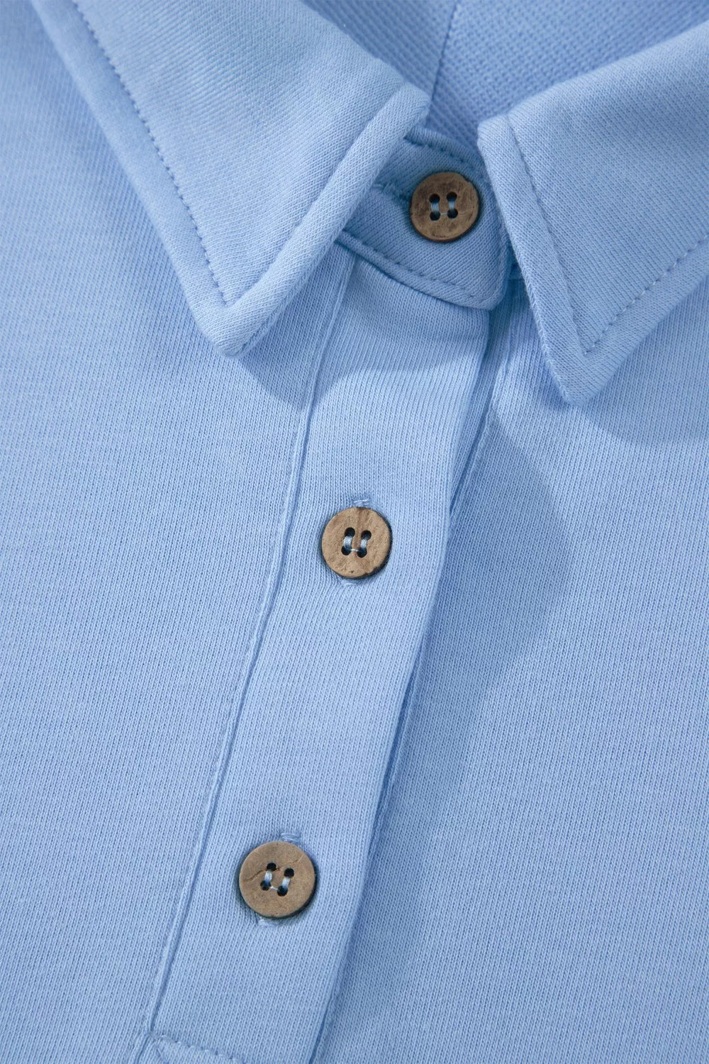 Light blue sleeveless polo shirt with wooden buttons and collar detail