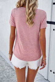 Blush pink V-neck tee with short sleeves and a cutout detail, worn with white frayed shorts.