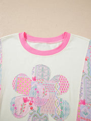 Maternity t-shirt with floral patchwork applique and pink crew neck.