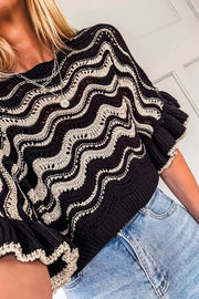 Black openwork knit sweater with cream wavy pattern and ruffled sleeves.