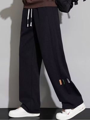 Men's black casual loose fit drawstring sweatpants with colorful side tags.