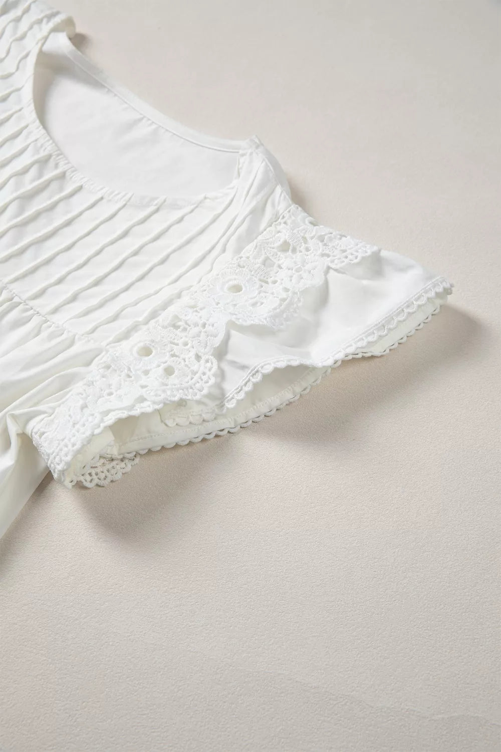 White cotton shirt with lace flutter sleeves and pleated front detail.