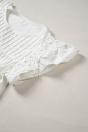 White cotton shirt with lace flutter sleeves and pleated front detail.