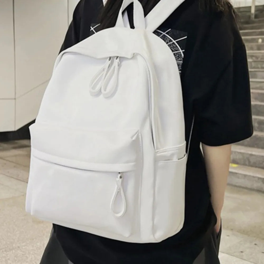 White leather backpack with front zip pocket and dual zip main compartment.