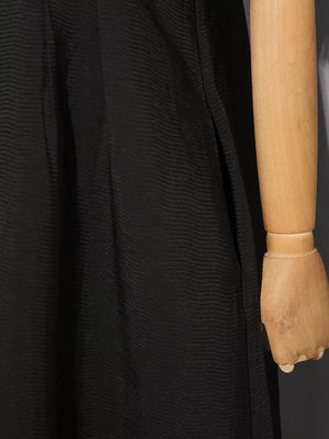 Black midi dress with textured fabric and a side slit detail.
