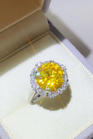 Radiant halo ring with a large yellow gemstone and surrounding clear stones.