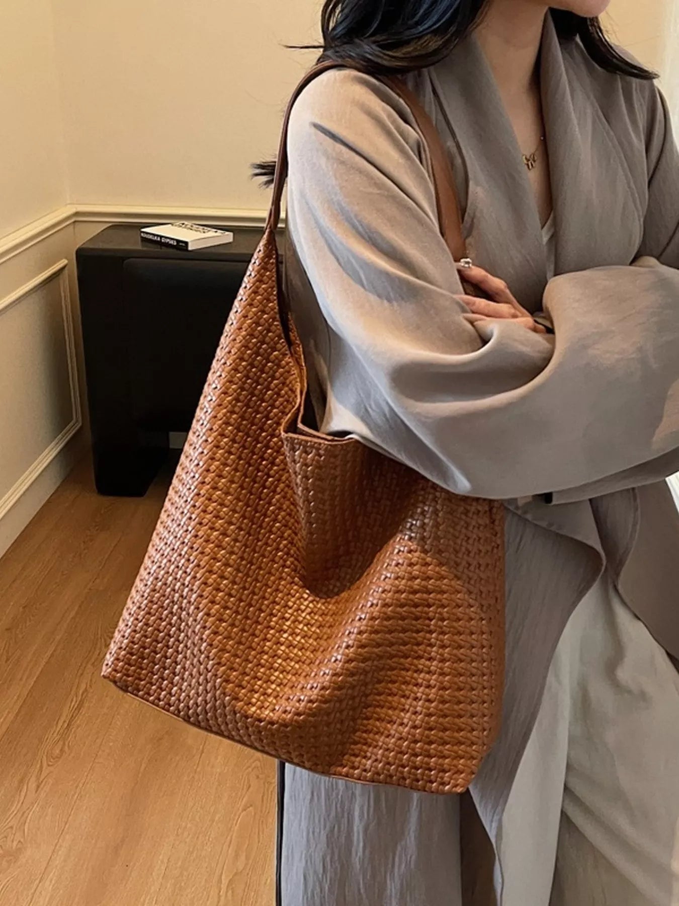 Brown woven straw texture tote bag with leather strap, styled on a woman.