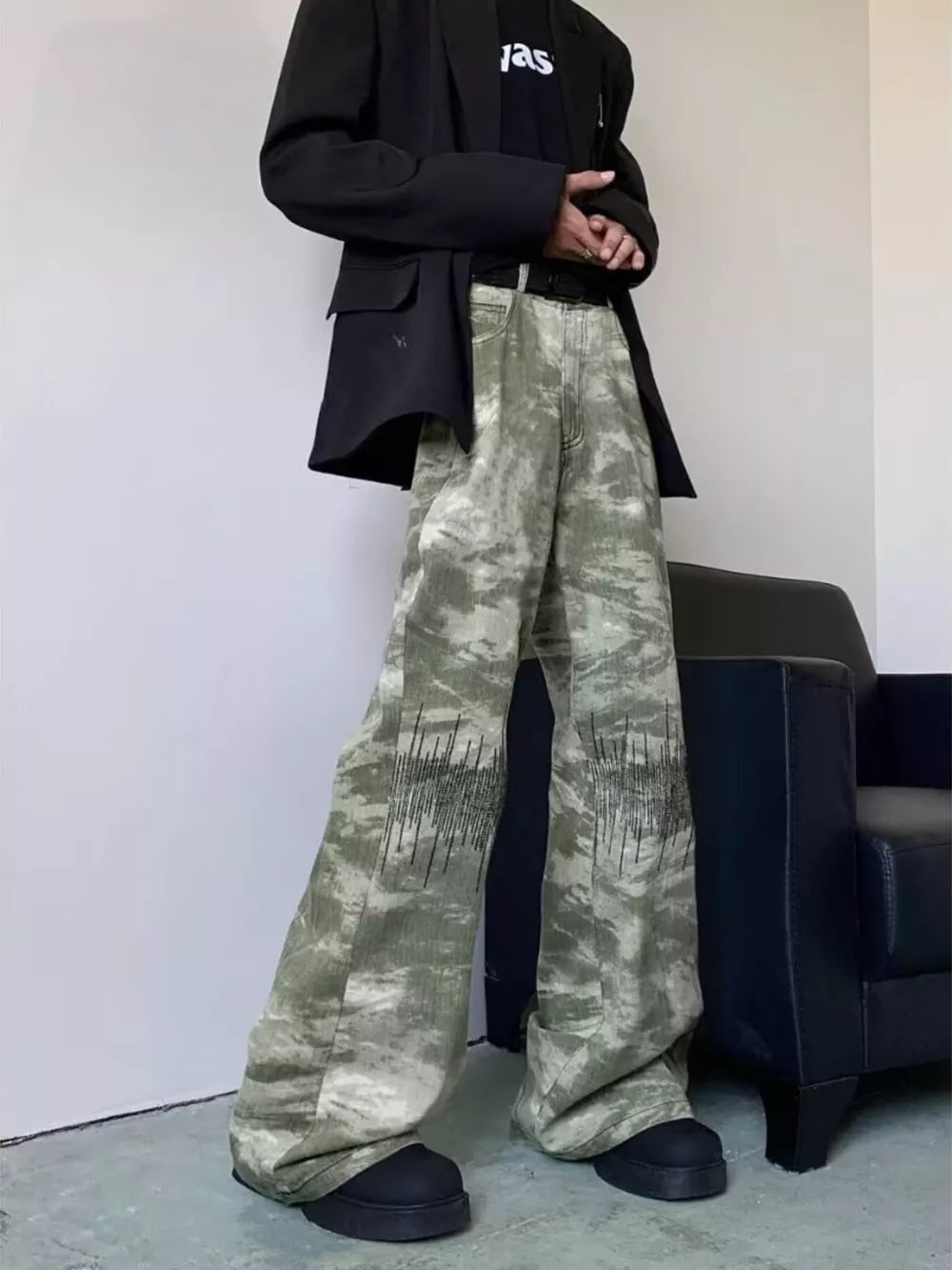Abstract print wide-leg jeans in green and white camouflage with black embroidered detail.