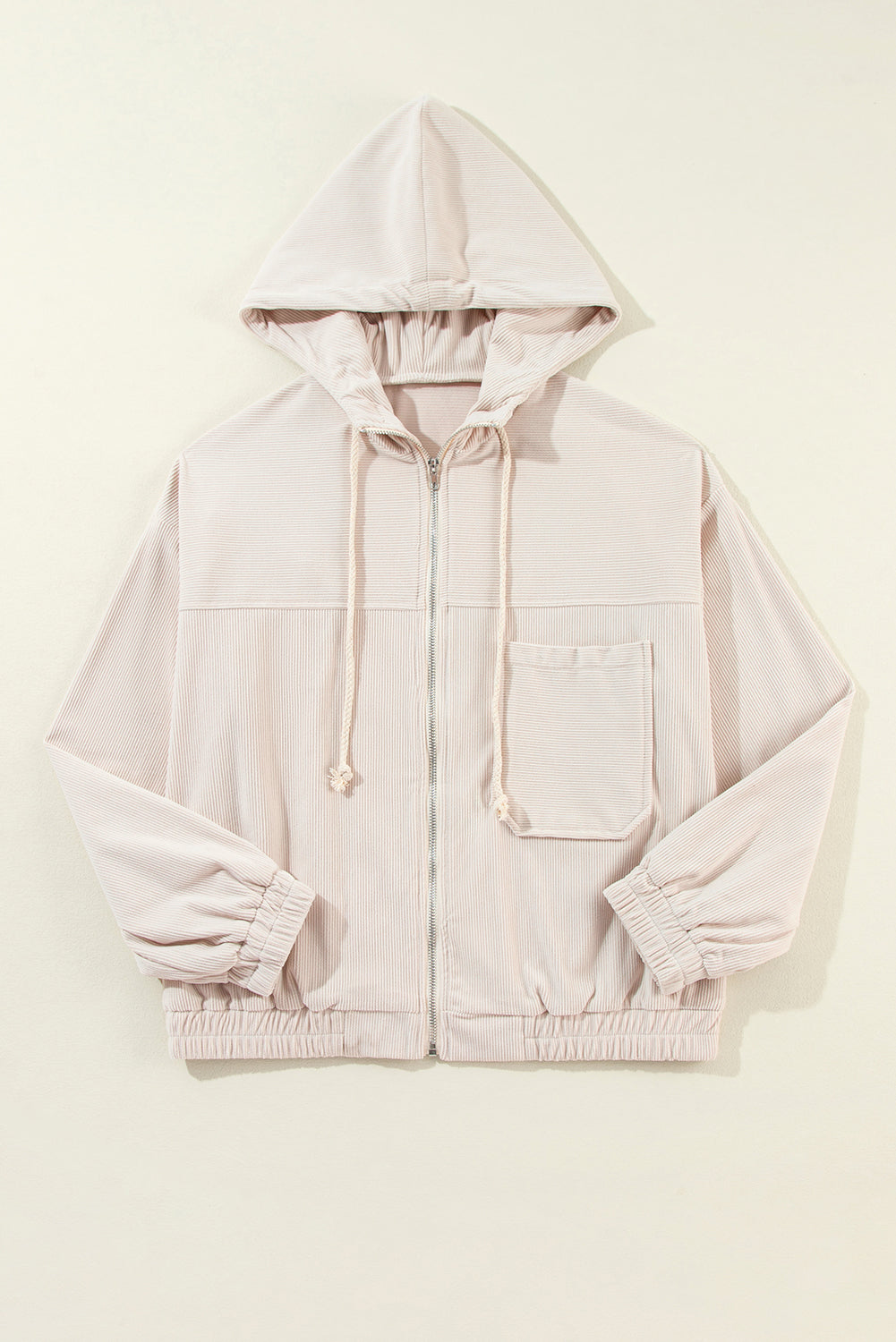 Cream corduroy bomber hoodie with relaxed fit, zip front, drawstring hood, chest pocket and elastic cuffs.