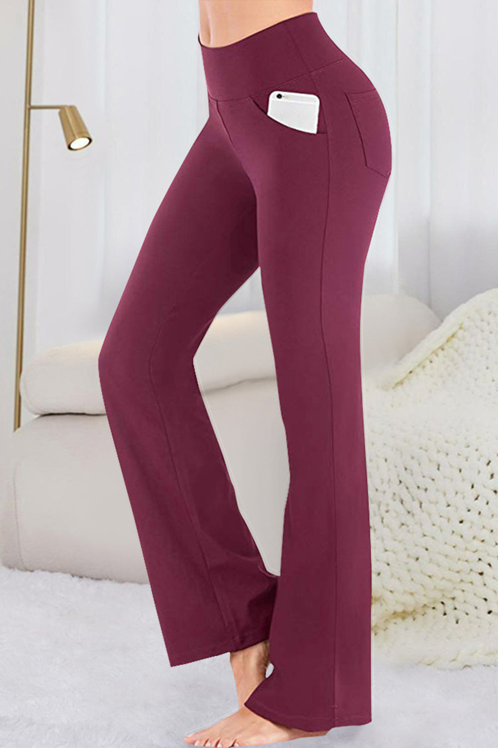 Burgundy flare-leg performance trousers with side pockets holding a smartphone.