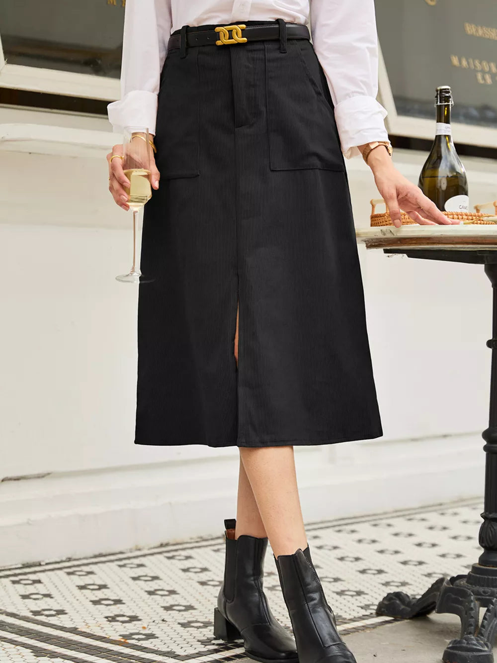Black midi skirt with vertical ribbing, buttoned front, and a front slit.